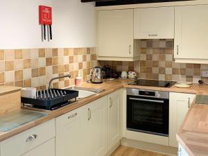 a kitchen with white cabinets and a sink at Rock Cottage in Crosthwaite