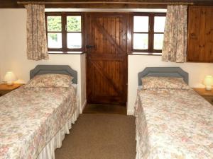 two beds in a room with two windows at Barrowmead Cottage - E2377 in Banwell