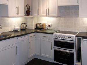 a kitchen with white cabinets and a stove top oven at School Knott Cott in Windermere