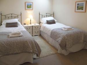 a bedroom with two beds and a dresser with towels at School Knott Cott in Windermere +1 photo