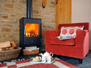 een woonkamer met een rode stoel en een open haard bij Ria's Cottage in Landshipping