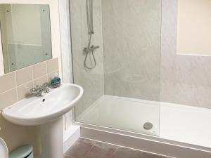 Un baño blanco con ducha y lavabo. en Little Barn - Hw7615, en Bettws-yn-Rhôs