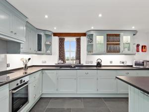 eine Küche mit weißen Schränken und einer Arbeitsplatte in der Unterkunft Temple Barn in Abercastle