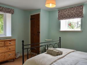 a bedroom with a bed and a dresser and two windows at Fairlaw Garden Cottage in Reston +14 photos