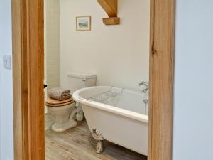 a bathroom with a white tub and a toilet at The Barn in Greystoke +4 photos
