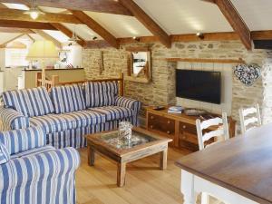 a living room with blue striped couches and a television at The Stables By The Sea in Newquay