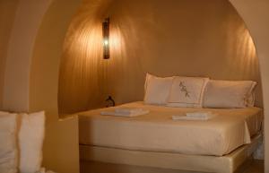 een bed met witte lakens en kussens in een kamer bij OIA UNIQUE HOMES by K&K in Oia