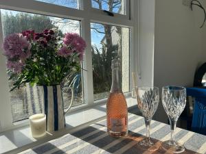 eine Flasche Wein und zwei Gläser und Blumen auf dem Tisch in der Unterkunft Westport Coastal Cottage in Westport + 9 Fotos