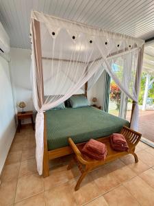 a bedroom with a bed with a canopy at Lodge Orchidée de la Villa La Palmira - Vue Mer - Jacuzzi Privé - Accès Piscine - Lit King Size - Clim - 4 étoiles - Proche commodités - TV - connectée - Internet fibre - Proche Plage in Les Anses-dʼArlets