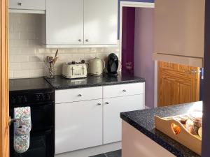 a kitchen with white cabinets and a black counter top at New House Farm Annexe in Neenton