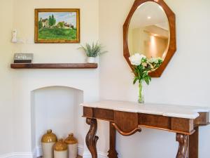 een badkamer met een wastafel met een spiegel en een vaas met bloemen bij Barnleigh in Ludlow