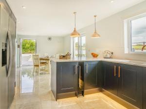 a kitchen with dark blue cabinets and a kitchen island at Penlon Cwrws in Llangynllo +30 photos