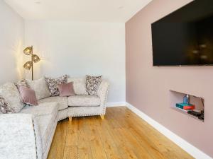 a living room with a couch and a flat screen tv at Penlon Cwrws in Llangynllo