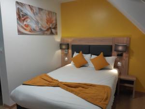 a bedroom with a large white bed with orange pillows at Hôtel NOROTEL in Brumath