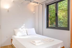 a white bedroom with a bed with two towels on it at Central cozy garden flat in Mesochórion