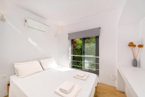 a white bedroom with a bed and a window at Central cozy garden flat in Mesochórion