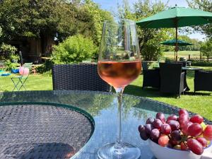 una copa de vino sentada en una mesa con un tazón de uvas en Blue Charm - 29585, en Damerham 6 fotos más