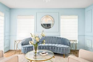 a living room with a blue couch and a table with flowers at Downtown 10 min, 90 degree F Pool & Spa, Linked 2 homes, Gated Parking in Houston