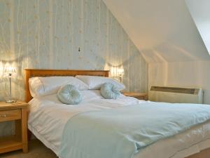 a bedroom with a white bed with blue pillows at Herdwick Heights in Keswick