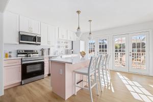 a kitchen with white cabinets and a island with bar stools at Downtown 10 min, 90 degree F Pool & Spa, Linked 2 homes, Gated Parking in Houston