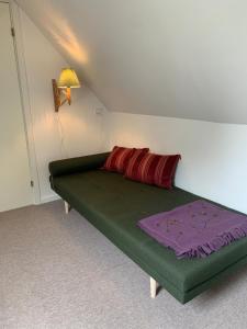 a bedroom with a green bed with a red pillow at Stone house with direct access to Haraldsted Lake in Ringsted +25 photos