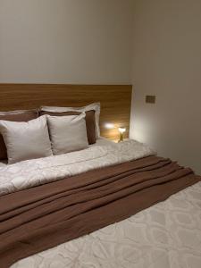 Una cama grande con almohadas blancas y una lámpara. en Roma chalet استراحة روما بدية, en Al Raka 2 fotos más