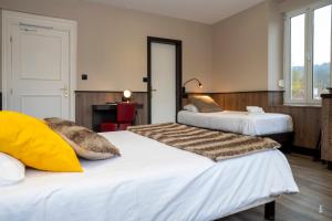 Habitación con 2 camas y escritorio. en Logis Hotel Des Bains, en Gérardmer