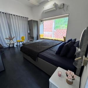 a bedroom with a large bed and a window at Casa Oceanus - Sea Facing Forest View Room - Ganpatipule in Nevra