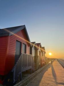 a row of houses on the beach at sunset at Surf & Stay - Muizenberg Beach in Muizenberg