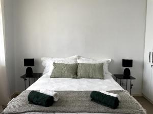a white bed with two green pillows on it at Surf & Stay - Muizenberg Beach in Muizenberg