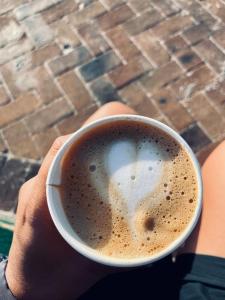 a person is holding a cup of coffee at Surf & Stay - Muizenberg Beach in Muizenberg