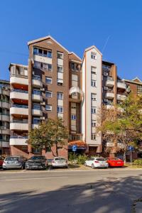 a large apartment building with cars parked in a parking lot at Ada Home Belgrade Apartment 