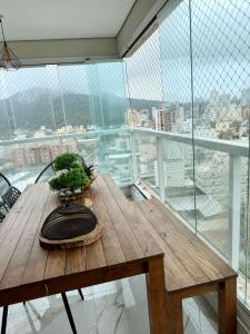 une table en bois devant une grande fenêtre dans l'établissement Lindo apartamento 124C com vista mar e lazer de clube, à Guarujá 19 autres photos