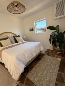 a bedroom with a large bed and a window at Seaside Garden Cottage Schoenmakerskop in Gqeberha