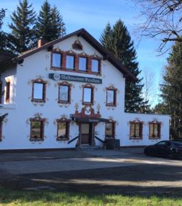 a white building with windows and a car parked in front at Pension Zollhaus in Oy-Mittelberg