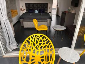 a bedroom with a bed and two yellow chairs and tables at Casa Oceanus - Sea Facing Forest View Room - Ganpatipule in Nevra +5 photos