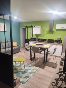 Una cocina y una sala de estar con mesa y sillas. en Cosy F2 proche parc thermal VITTEL, en Vittel