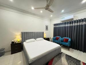 a bedroom with a bed and a blue chair at Cozy & Peaceful Rooms Near Lyallpur Galleria in Faisalabad