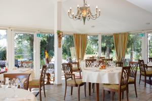 uma sala de jantar com mesas e cadeiras e um lustre em Landgasthof Gut Marienbildchen em Roetgen