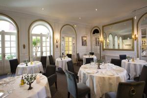een restaurant met witte tafels en stoelen en een spiegel bij Hotel d'Europe in Avignon