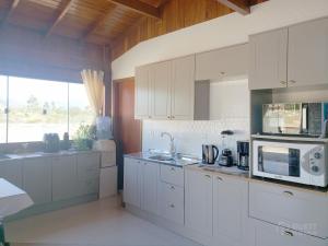 a kitchen with white cabinets and a microwave at Casa de Madeira Encantadora in Governador Celso Ramos +22 photos