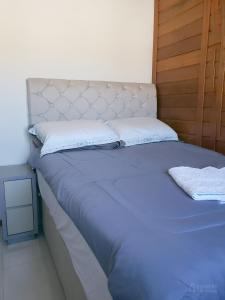 a bed with blue sheets and white pillows at Casa de Madeira Encantadora in Governador Celso Ramos