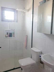 a white bathroom with a toilet and a shower at Casa de Madeira Encantadora in Governador Celso Ramos