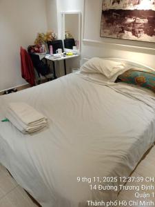 a large white bed in a room with a desk at Financee Hotel 10 in Ho Chi Minh City