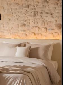 a bedroom with a white bed with a stone wall at Elounda Heights (Adults Only) in Elounda +84 photos