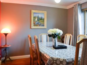 a dining room table with a vase of flowers on it at Ty Glyndwr in Ystalyfera
