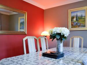a table with a vase with white flowers on it at Ty Glyndwr in Ystalyfera