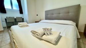 a bedroom with a large white bed with towels on it at Fronte Mare Ampio Quadrilocale in Alassio +25 photos