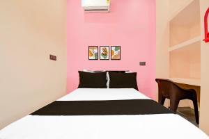 a pink bedroom with a bed and a desk at Hotel O Welcome Guest House in Patna