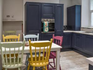 eine Küche mit bunten Stühlen, einem Tisch und einem Herd in der Unterkunft Ty Isaf in Barmouth + 17 Fotos
